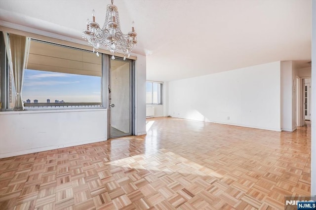 unfurnished room with light parquet floors and a chandelier