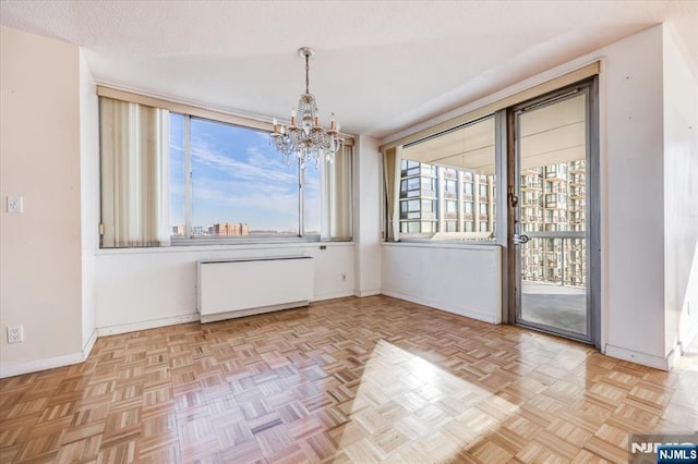 unfurnished dining area with an inviting chandelier, light parquet flooring, radiator heating unit, and a textured ceiling