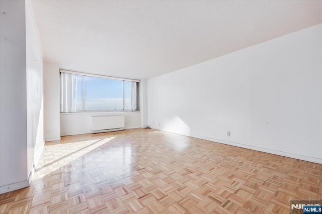 empty room featuring radiator and light parquet floors