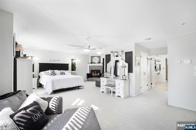 bedroom featuring ceiling fan, a tiled fireplace, and light carpet