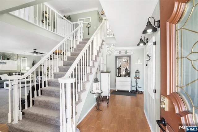 staircase with ceiling fan, ornamental molding, and wood-type flooring