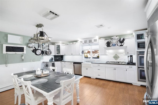 kitchen with light wood-type flooring, white cabinets, and appliances with stainless steel finishes