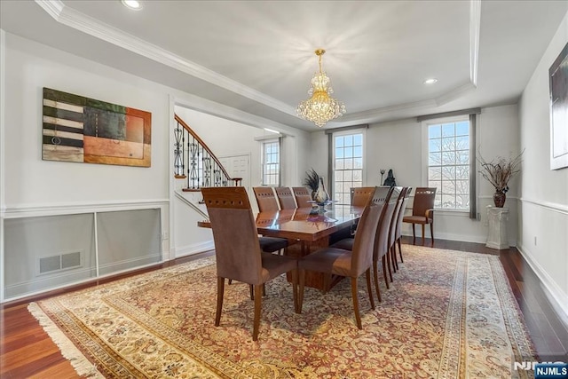 dining area featuring crown molding, hardwood / wood-style flooring, a tray ceiling, and a chandelier