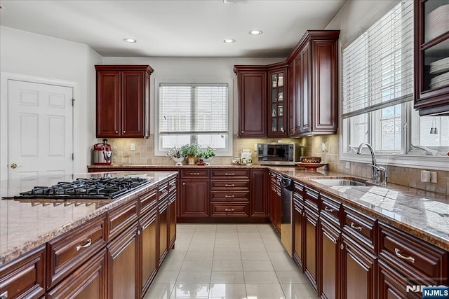 kitchen featuring tasteful backsplash, sink, light tile patterned floors, light stone counters, and stainless steel appliances