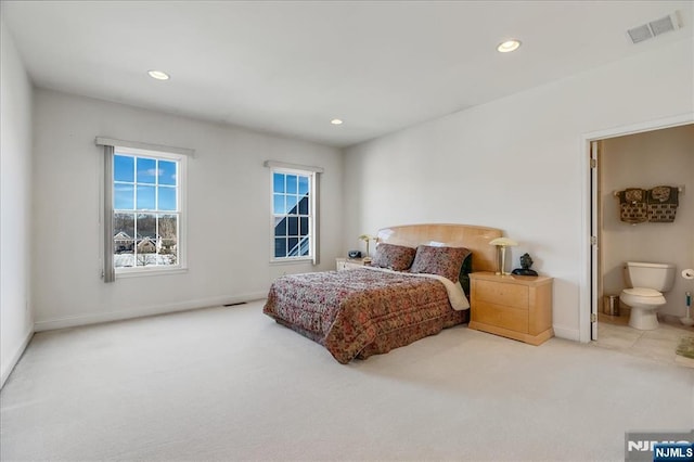 bedroom featuring ensuite bathroom and light carpet