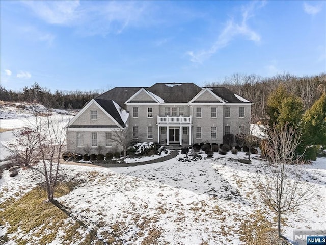 snow covered house featuring a balcony