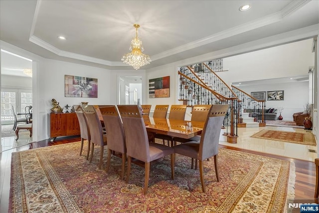 dining space with hardwood / wood-style flooring, crown molding, an inviting chandelier, and a tray ceiling