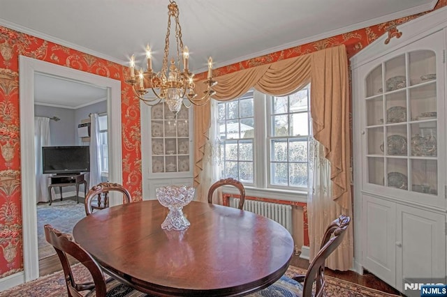 dining area with an inviting chandelier, hardwood / wood-style flooring, radiator heating unit, and ornamental molding