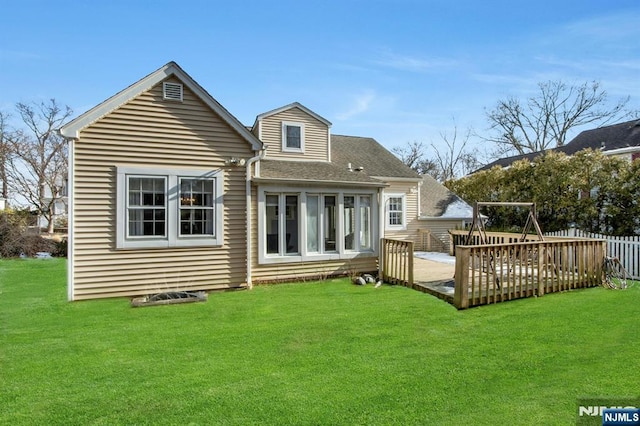 rear view of property with a deck and a lawn