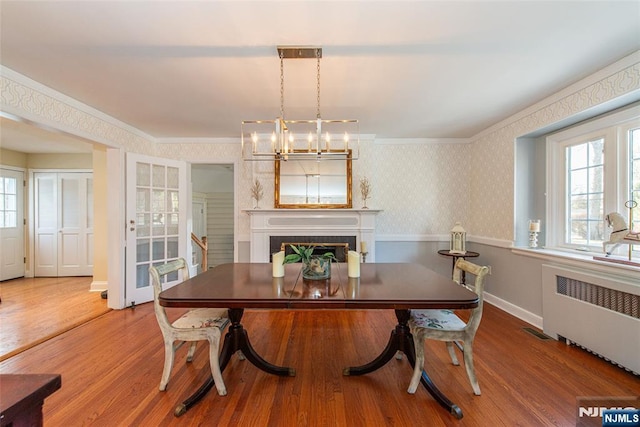 dining space with hardwood / wood-style flooring, ornamental molding, plenty of natural light, and radiator