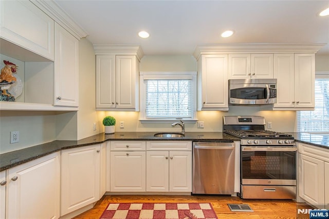 kitchen with a healthy amount of sunlight, appliances with stainless steel finishes, sink, and white cabinets