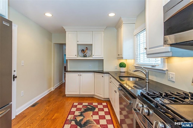 kitchen featuring appliances with stainless steel finishes, sink, white cabinets, and light hardwood / wood-style floors