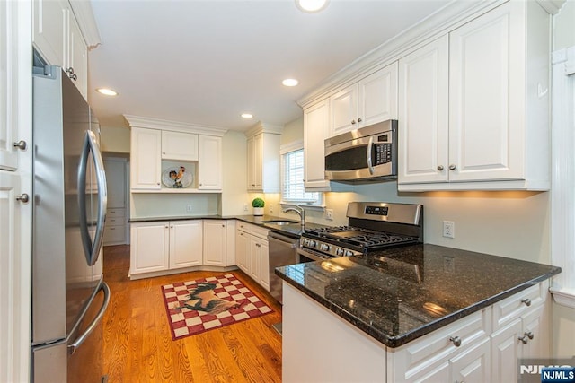 kitchen with sink, light hardwood / wood-style flooring, stainless steel appliances, and white cabinets