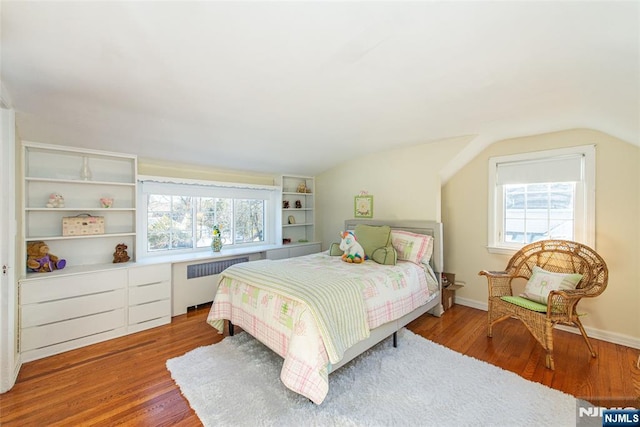 bedroom featuring multiple windows, radiator, and light wood-type flooring