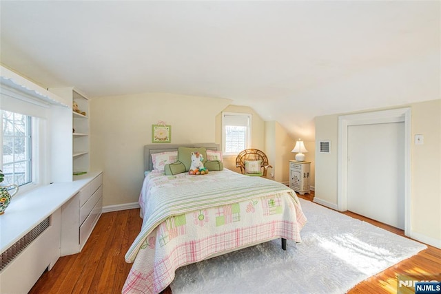 bedroom featuring hardwood / wood-style flooring, lofted ceiling, and radiator