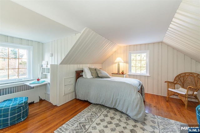 bedroom with vaulted ceiling, radiator heating unit, and hardwood / wood-style floors