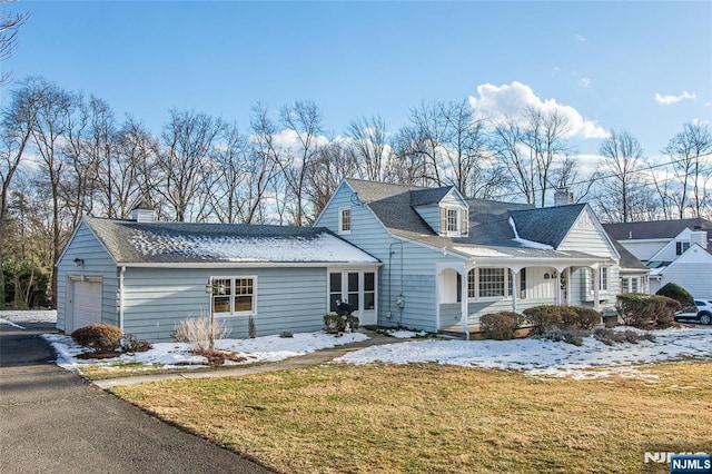 cape cod-style house featuring a garage, a porch, and a yard