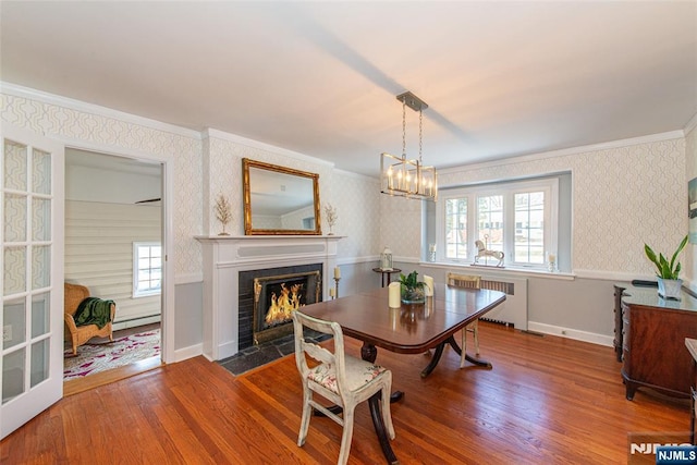 dining room with radiator, hardwood / wood-style flooring, ornamental molding, and baseboard heating