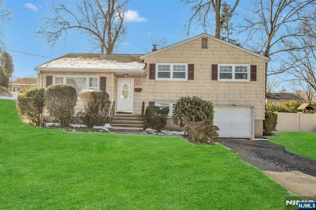 split level home with a garage and a front lawn