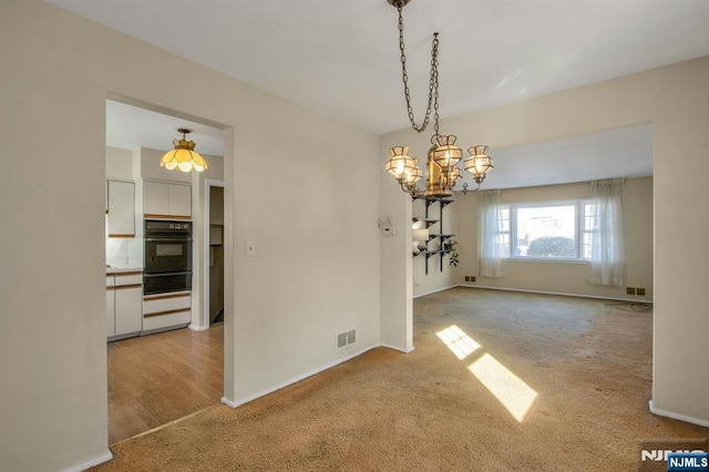 unfurnished dining area featuring light colored carpet and a chandelier