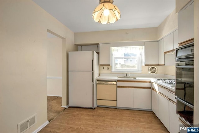 kitchen featuring white cabinetry, white appliances, sink, and light hardwood / wood-style flooring