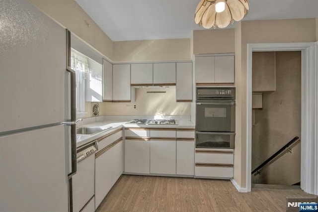 kitchen featuring white appliances, sink, light hardwood / wood-style floors, and white cabinets