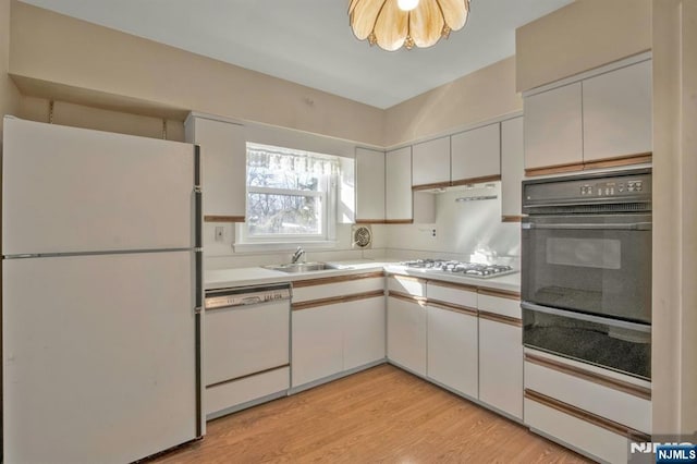 kitchen featuring white cabinetry, white appliances, light hardwood / wood-style floors, and sink