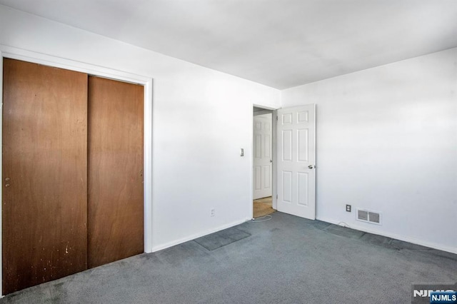 unfurnished bedroom featuring a closet and dark colored carpet