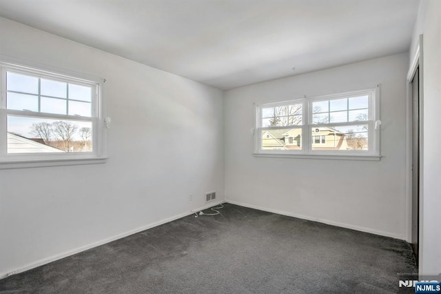 spare room with dark colored carpet