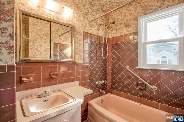 bathroom with tile walls, vanity, and tiled shower / bath