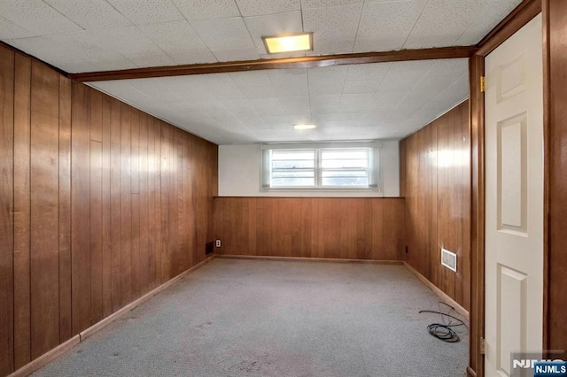 carpeted spare room with wood walls