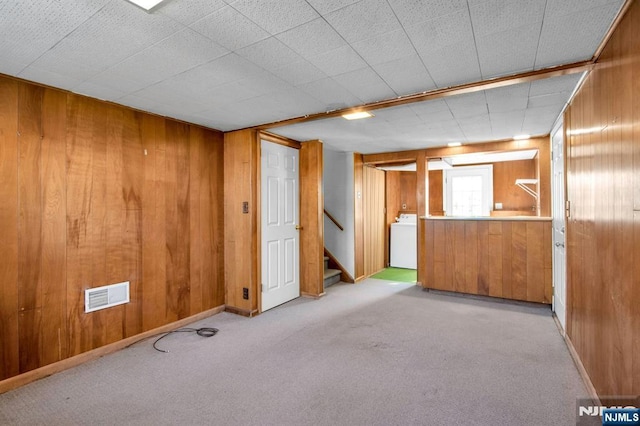 carpeted empty room with washer / dryer and wooden walls