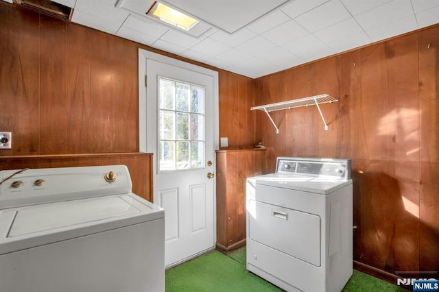 laundry room featuring light colored carpet, washing machine and clothes dryer, and wood walls