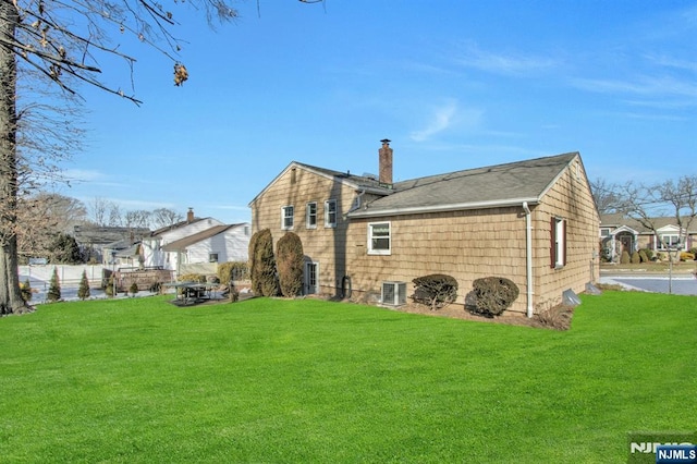 rear view of property with central AC and a lawn