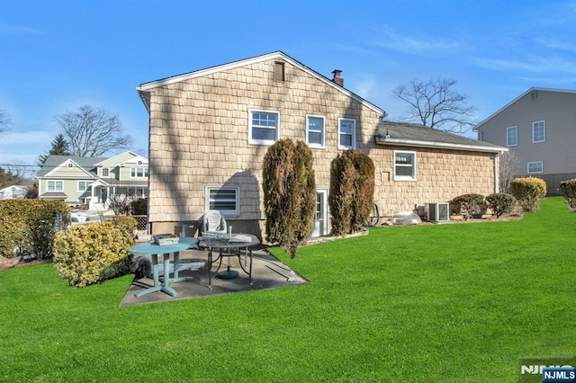 back of property featuring a lawn, central air condition unit, and a patio area