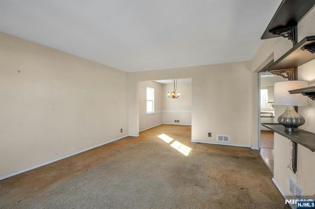 unfurnished living room with light carpet and a notable chandelier