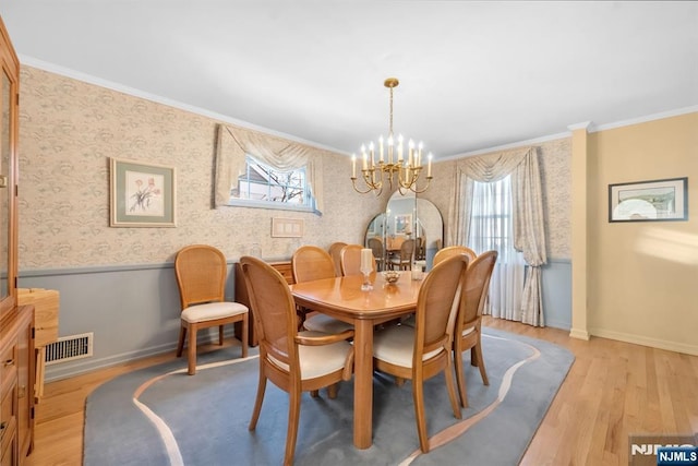 dining space featuring crown molding, a chandelier, and light wood-type flooring