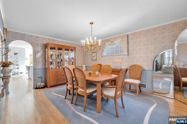 dining area featuring ornamental molding, a chandelier, and light hardwood / wood-style flooring