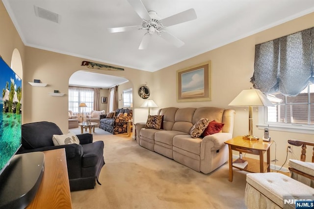 living room with ceiling fan, ornamental molding, and carpet