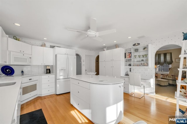 kitchen featuring white cabinetry, white appliances, a kitchen island, and light hardwood / wood-style flooring