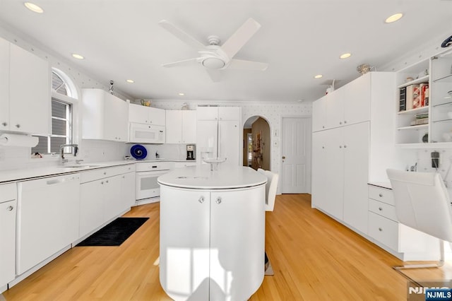 kitchen with sink, white appliances, white cabinetry, light hardwood / wood-style floors, and a kitchen island