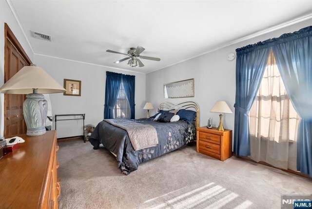 bedroom featuring crown molding, ceiling fan, light carpet, and multiple windows