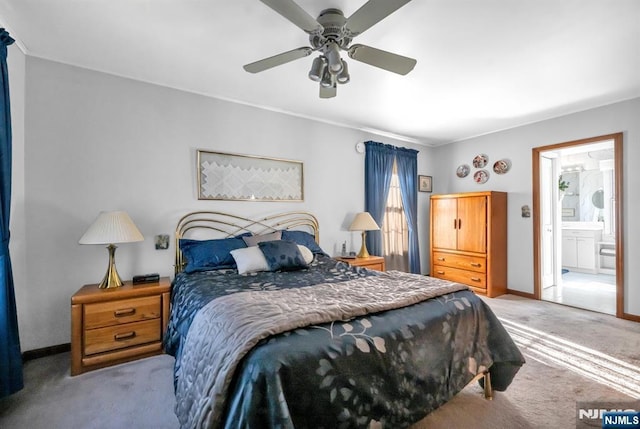 bedroom with ceiling fan, light colored carpet, and ensuite bath