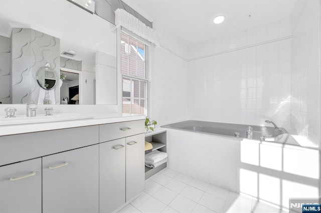 bathroom featuring tile patterned flooring, vanity, tiled bath, and tile walls