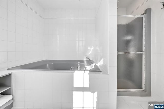 bathroom featuring plus walk in shower and tile walls