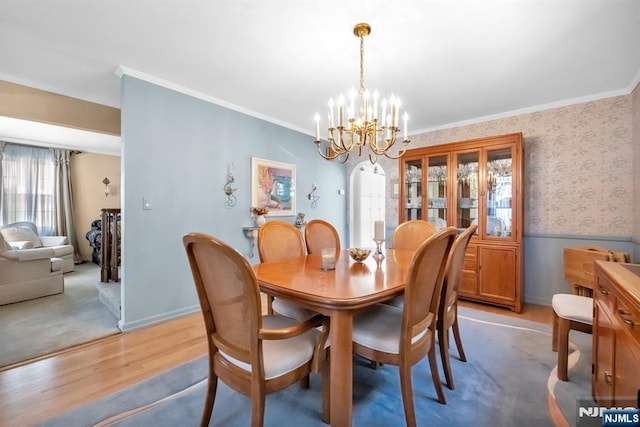 dining area featuring ornamental molding, an inviting chandelier, and light hardwood / wood-style floors