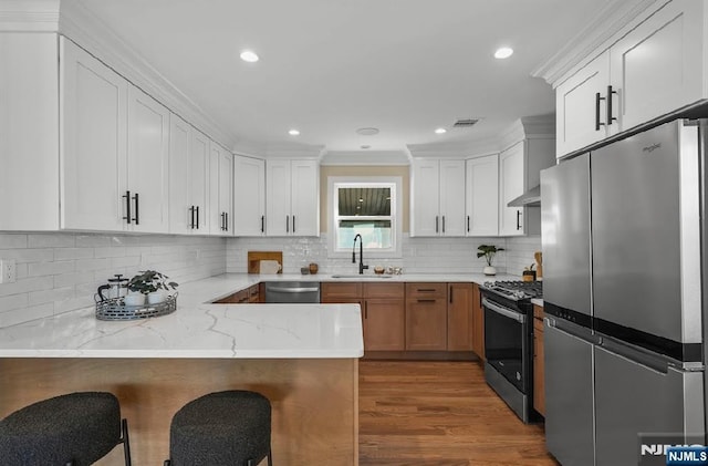 kitchen featuring white cabinetry, sink, kitchen peninsula, stainless steel appliances, and light stone countertops