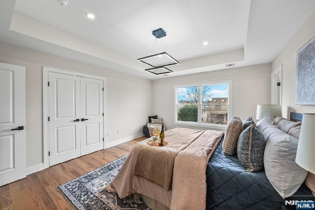 bedroom featuring hardwood / wood-style floors and a tray ceiling