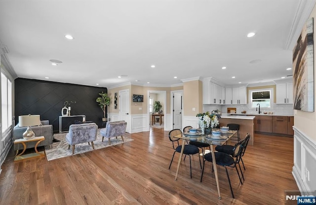 dining area with ornamental molding, sink, and light hardwood / wood-style flooring