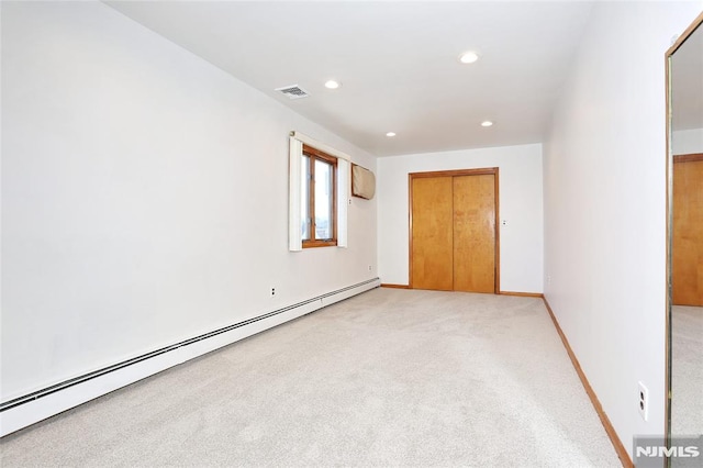 carpeted spare room with a baseboard radiator and a wall mounted AC